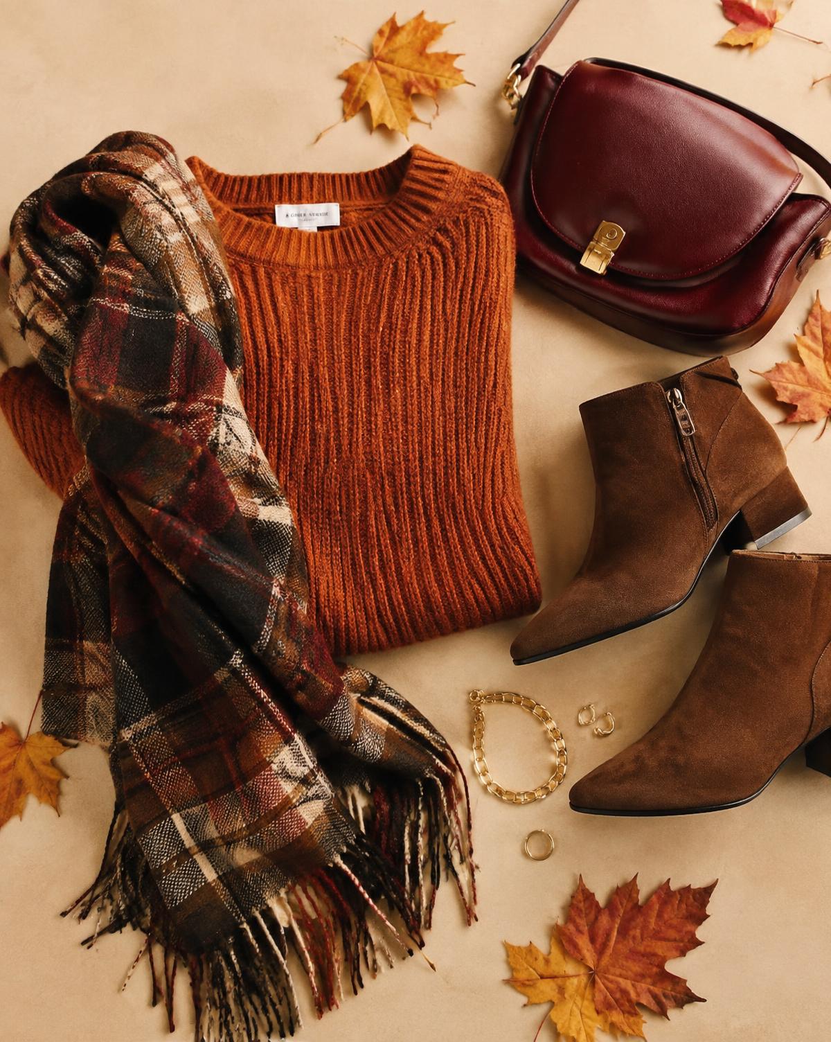 Autumn flat lay with rust knit, plaid scarf, suede boots and burgundy bag